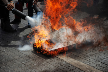 Live flame erupting from a training tray as a trainee opens an extinguisher